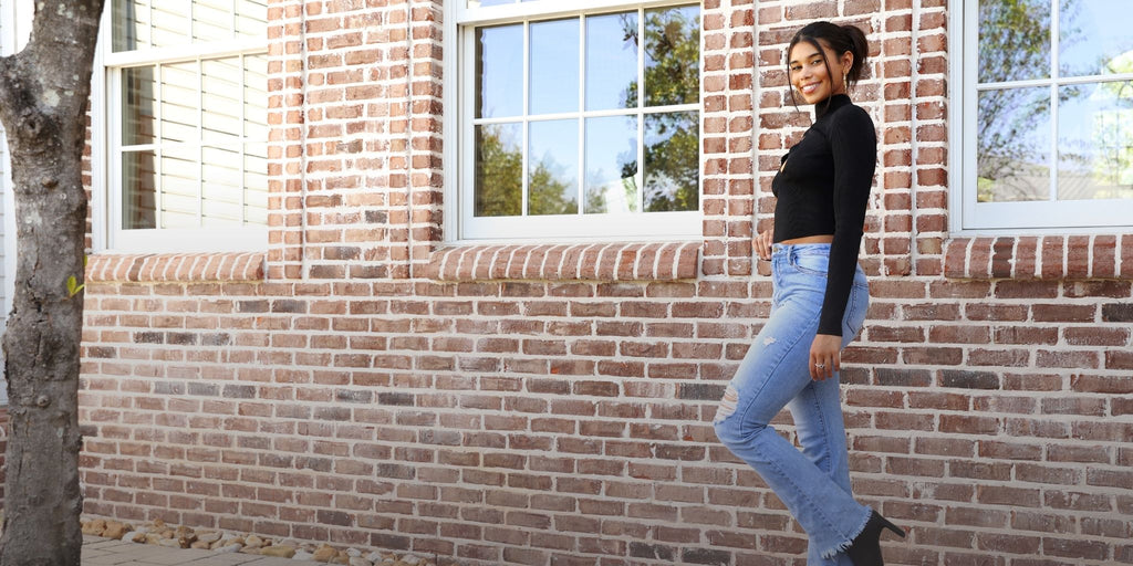 Desktop image of woman wearing avenue des champs outfit, Ciao Babe Ribbed Mock Neck Cutout Top, standing in front of a brick wall
